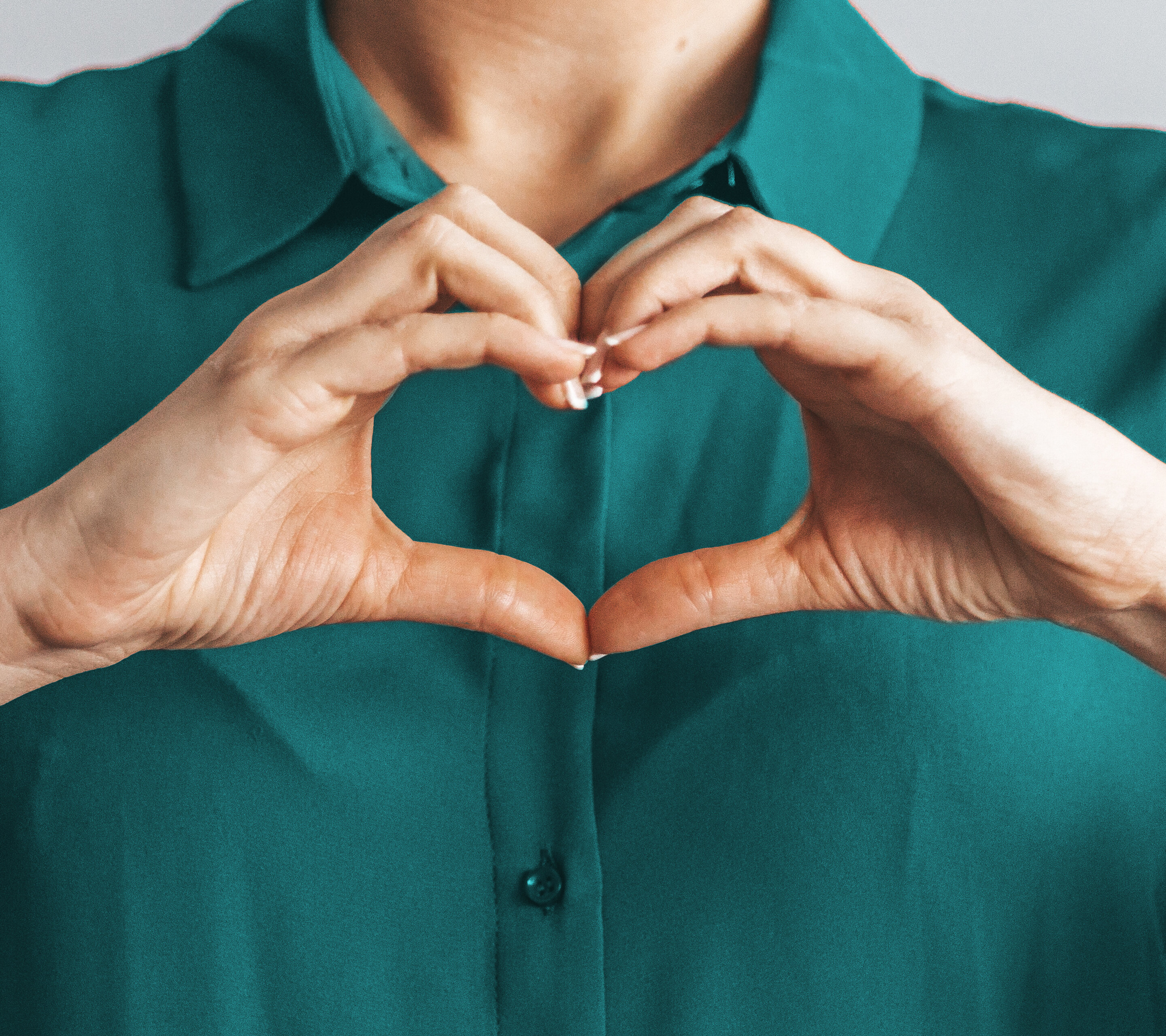 Woman with blouse makes a heart with her hands