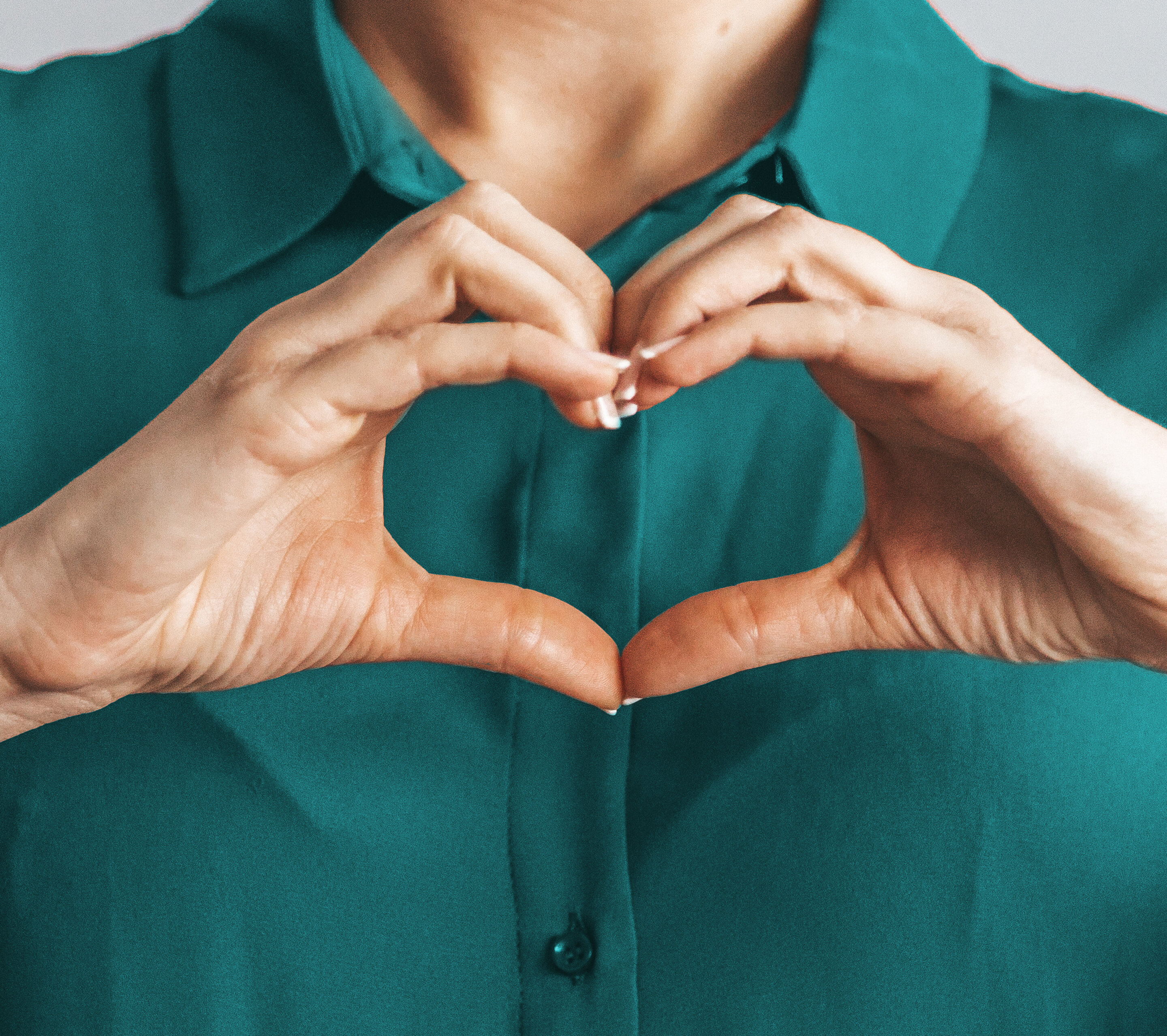 Frau mit Bluse macht Herz mit Händen